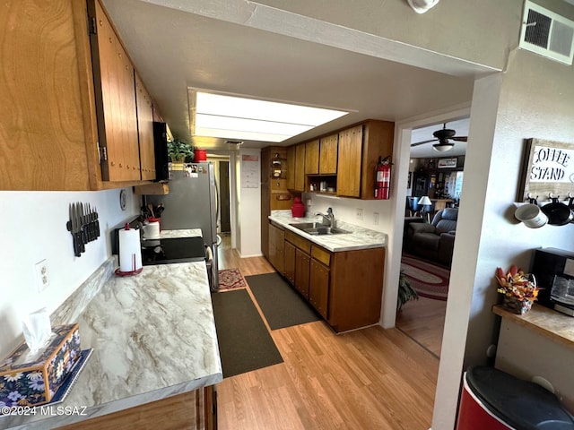 kitchen featuring ceiling fan, light wood-type flooring, sink, and range