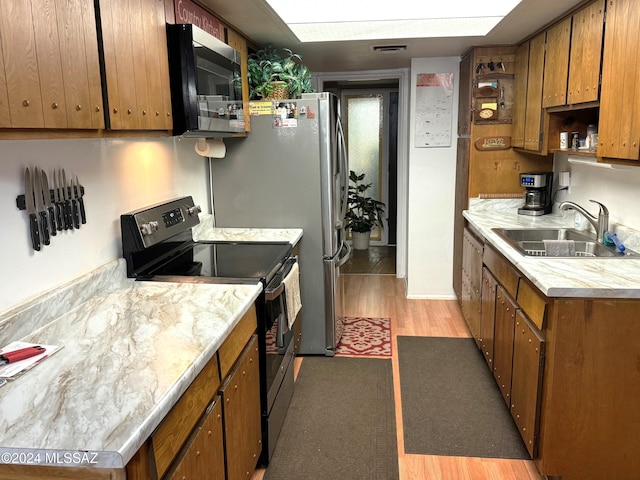 kitchen with sink, stainless steel appliances, and light hardwood / wood-style floors