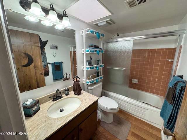 full bathroom featuring combined bath / shower with glass door, wood-type flooring, vanity, and toilet