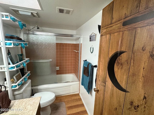 full bathroom featuring enclosed tub / shower combo, toilet, wood-type flooring, and vanity