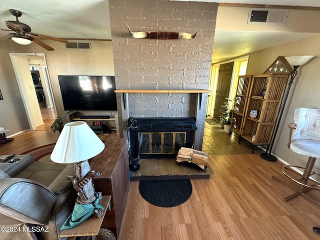 living room with hardwood / wood-style flooring, ceiling fan, and stacked washer / dryer