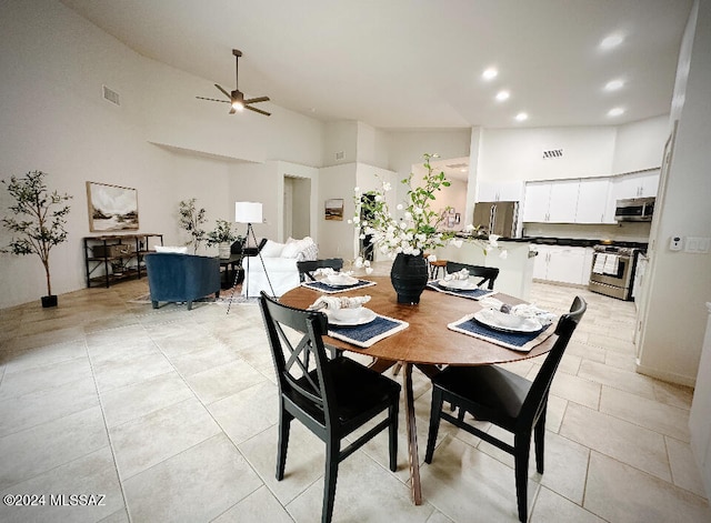 tiled dining room with ceiling fan and high vaulted ceiling