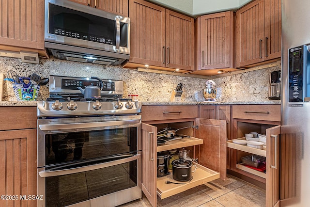 kitchen with light stone counters, appliances with stainless steel finishes, decorative backsplash, and light tile patterned floors