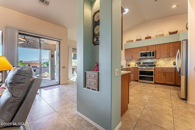 kitchen with tasteful backsplash, lofted ceiling, stainless steel appliances, and light tile patterned floors