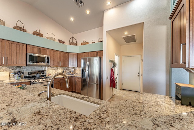 kitchen featuring sink, appliances with stainless steel finishes, backsplash, high vaulted ceiling, and light stone counters