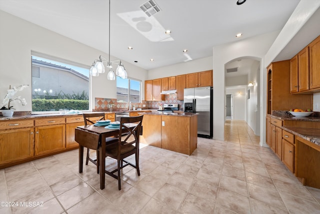 kitchen featuring a kitchen island, brown cabinetry, visible vents, and stainless steel appliances