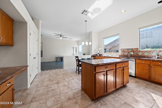 kitchen featuring visible vents, brown cabinets, a sink, backsplash, and stainless steel dishwasher