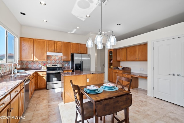 kitchen featuring sink, a center island, light stone counters, pendant lighting, and appliances with stainless steel finishes