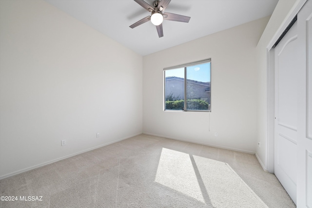 unfurnished bedroom with baseboards, light carpet, and ceiling fan