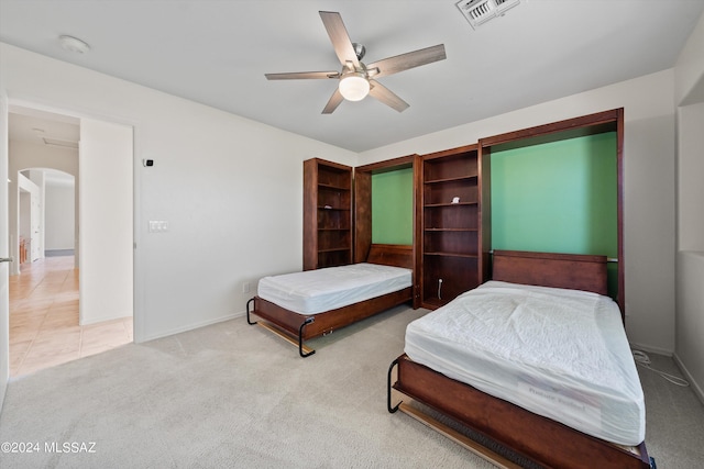 bedroom featuring visible vents, a ceiling fan, arched walkways, carpet floors, and baseboards