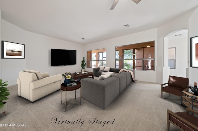 living area featuring light carpet, visible vents, arched walkways, and a ceiling fan