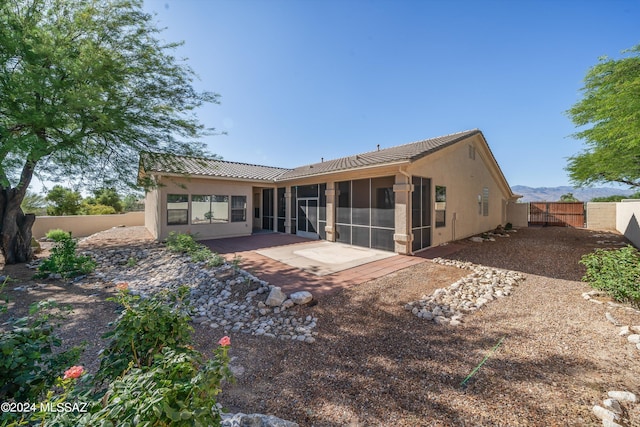 back of property featuring stucco siding, a fenced backyard, a patio area, a sunroom, and a tiled roof