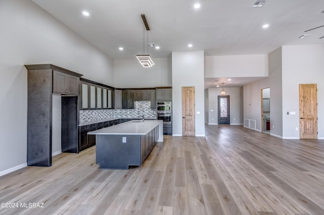 kitchen featuring a high ceiling, a kitchen island with sink, and decorative light fixtures