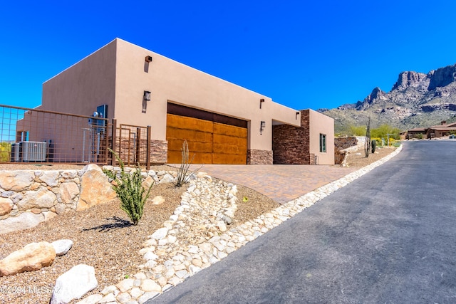 pueblo revival-style home featuring a garage, a mountain view, and central AC