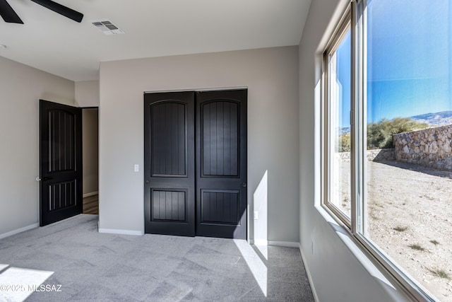 bedroom with ceiling fan, light colored carpet, and multiple windows