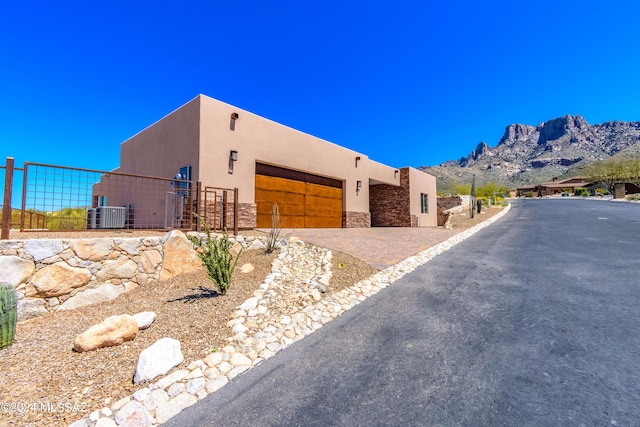 pueblo revival-style home featuring a garage, a mountain view, and central air condition unit