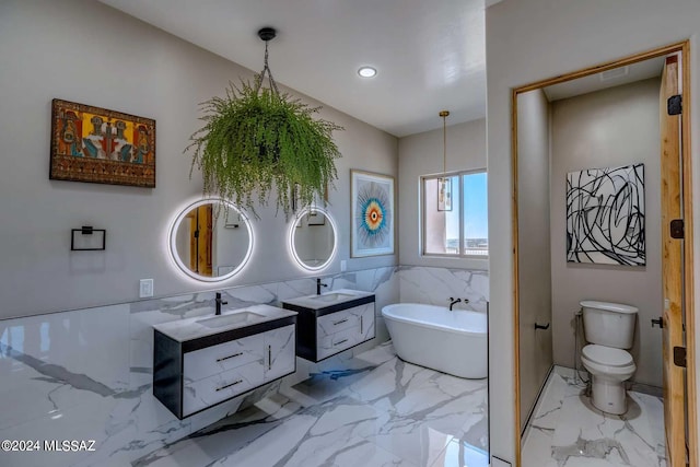 bathroom with tile walls, vanity, a bath, and toilet