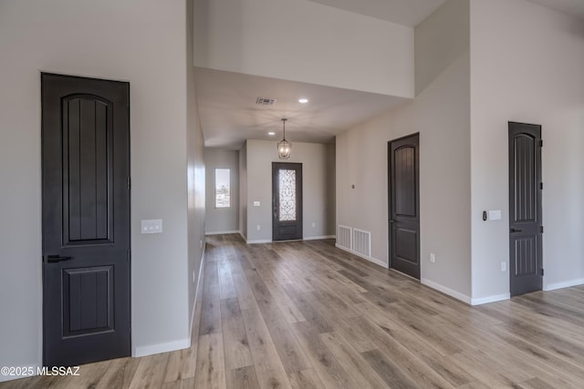 foyer with a towering ceiling and light wood-type flooring