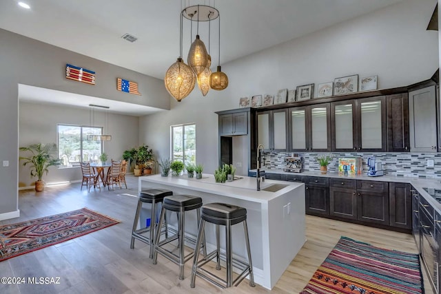 kitchen featuring sink, tasteful backsplash, a center island with sink, a kitchen breakfast bar, and a healthy amount of sunlight