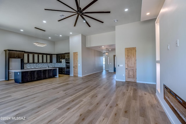 unfurnished living room with a towering ceiling and light wood-type flooring