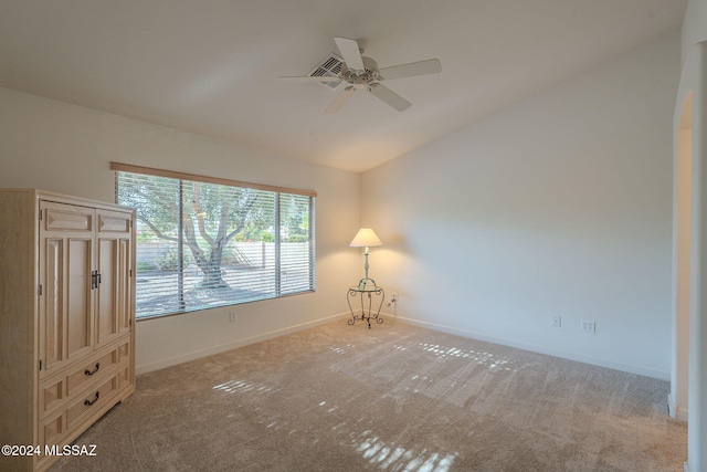 empty room with light carpet, ceiling fan, and vaulted ceiling