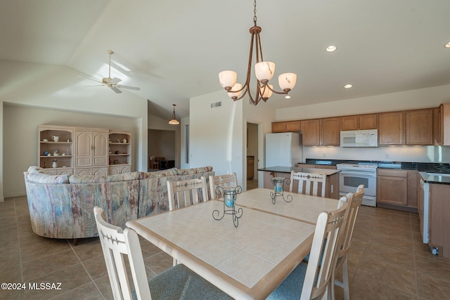 tiled dining space featuring ceiling fan with notable chandelier and vaulted ceiling