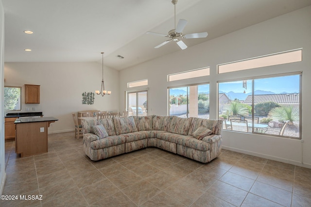 tiled living room featuring ceiling fan with notable chandelier, a mountain view, lofted ceiling, and a healthy amount of sunlight