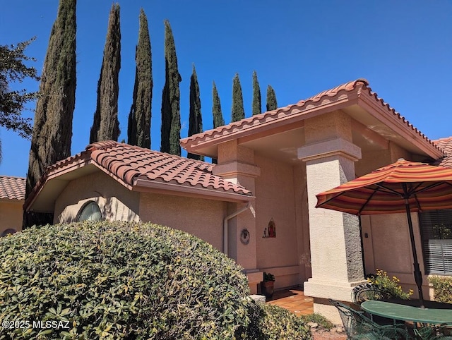 exterior space with a tile roof and stucco siding