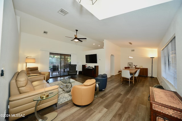 living room with arched walkways, vaulted ceiling, wood finished floors, and visible vents