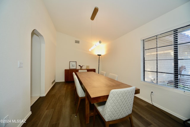 dining room featuring baseboards, visible vents, arched walkways, and dark wood finished floors