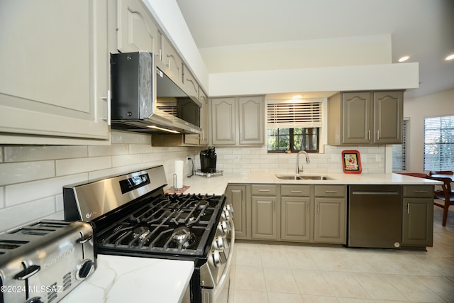 kitchen with light tile patterned floors, light countertops, backsplash, appliances with stainless steel finishes, and a sink