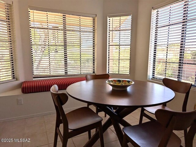 dining area with plenty of natural light, light tile patterned flooring, and baseboards