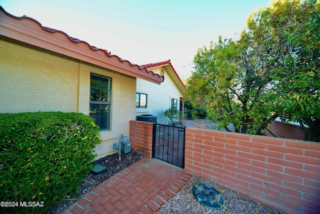 exterior space with a gate, fence, and central AC