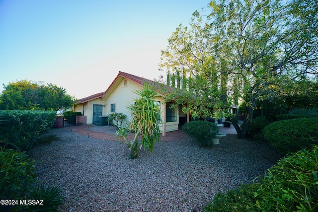 exterior space featuring a patio area, a tiled roof, central AC unit, and stucco siding