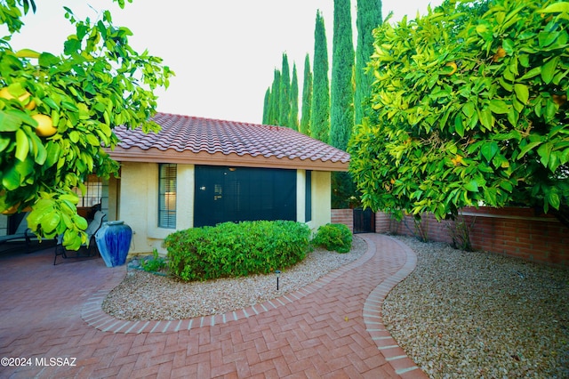 exterior space with a tile roof, fence, and stucco siding