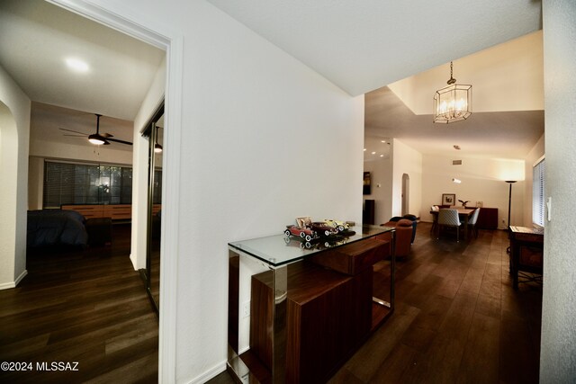 hallway featuring dark wood-type flooring, arched walkways, and a notable chandelier