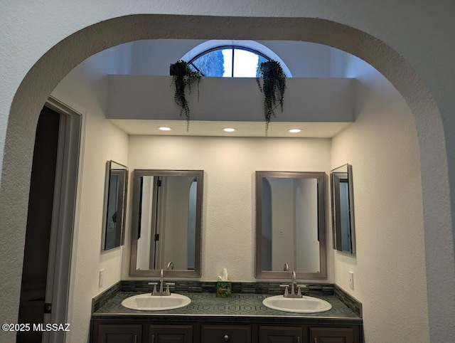 bathroom featuring a textured wall, a sink, and double vanity