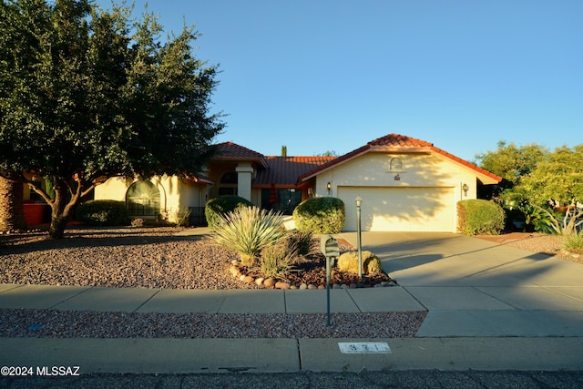 mediterranean / spanish-style house featuring a garage, a tile roof, driveway, and stucco siding