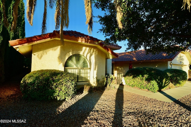 mediterranean / spanish home featuring a tiled roof and stucco siding