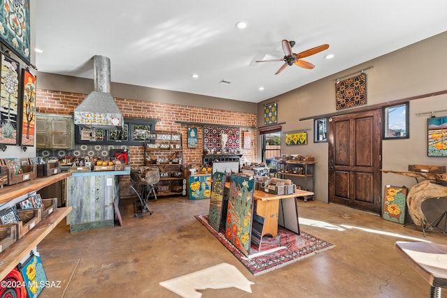 misc room featuring ceiling fan, brick wall, and concrete floors