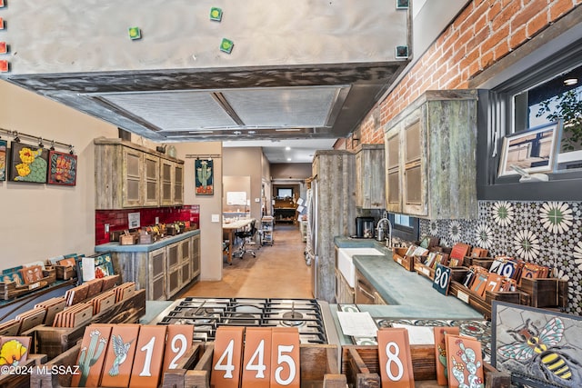 kitchen featuring beam ceiling, sink, and brick wall