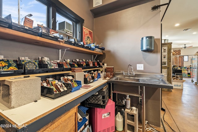 bar with a wealth of natural light, ceiling fan, concrete flooring, and stainless steel counters