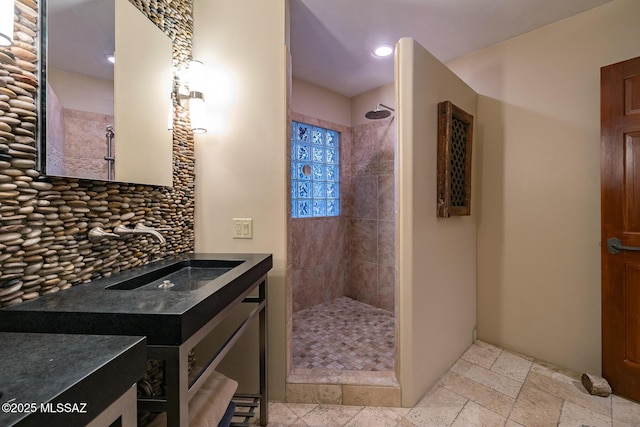 bathroom featuring tiled shower and vanity