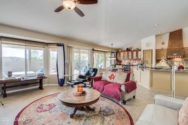 living room featuring light tile patterned flooring, ceiling fan, lofted ceiling, and sink