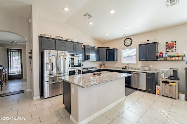 kitchen featuring light stone counters, stainless steel appliances, sink, a kitchen island, and lofted ceiling