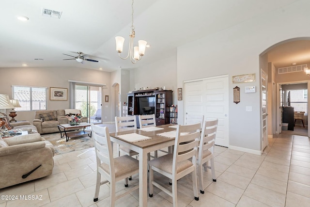 dining space with ceiling fan with notable chandelier, light tile patterned floors, and vaulted ceiling