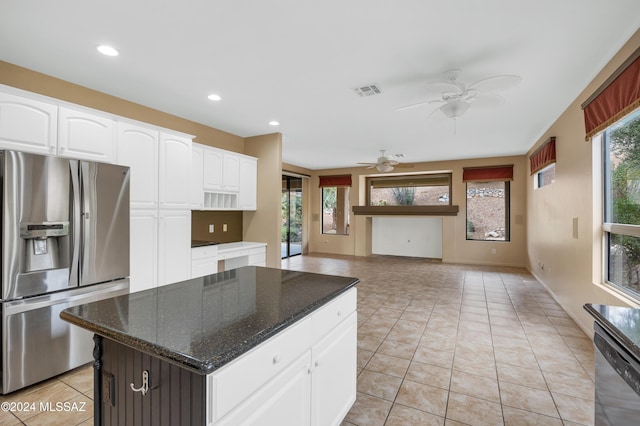 kitchen with appliances with stainless steel finishes, dark stone countertops, white cabinets, a kitchen island, and plenty of natural light