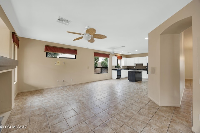 unfurnished living room featuring ceiling fan, light tile patterned floors, and sink