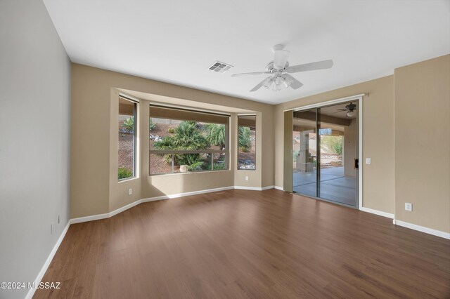 unfurnished room with dark hardwood / wood-style flooring, plenty of natural light, and ceiling fan