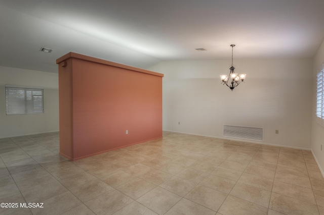 tiled empty room featuring vaulted ceiling and a chandelier